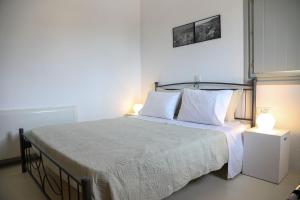 a bedroom with a bed with white sheets and two lamps at Vorino Luxury Villas in Psíon