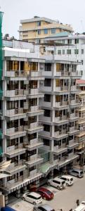 a large apartment building with cars parked in front of it at Sleep Inn Hotel - Kariakoo in Dar es Salaam