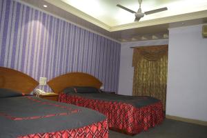 チッタゴンにあるAsian SR Hotelの紫の壁のホテルルーム(ベッド2台付)