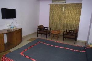 un soggiorno con tappeto, TV e sedie di Asian SR Hotel a Chittagong