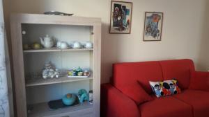 eine rote Couch neben einem Bücherregal in der Unterkunft Appartamento Centrale con garage in Asti