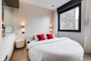 una camera da letto con un grande letto bianco con cuscini rossi di EMERALD Luxury Suite Apartment a Roma