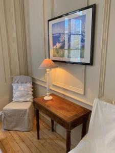a table with a lamp and a chair in a room at L'Annexe Apparthôtel du 11 A, 4 étoiles in Besançon