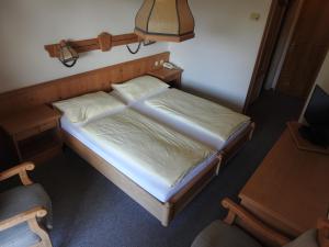 Cama pequeña en habitación con lámpara en Hotel Carossa bed&breakfast, en Sankt Gilgen