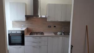 cocina con armarios blancos y fogones en Appartamento a Cecina mare, en Marina di Cecina