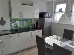 a kitchen with white cabinets and a table with chairs at Ferienwohnung Jasmin in Hannover