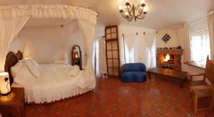 a bedroom with a large white bed and a blue chair at Posada Los Alcatraces in Atlixco