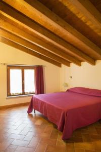 una camera con letto rosso in una stanza con soffitti in legno di CASA VACANZA VILLA DeA a Villafranca in Lunigiana