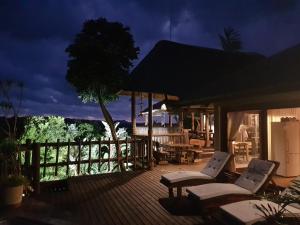 a deck with two white chairs and a tree at Ndiza Lodge and Cabanas in St Lucia