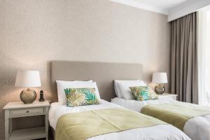 two beds in a hotel room with two lamps at Cesca's Boutique Hotel in Xlendi