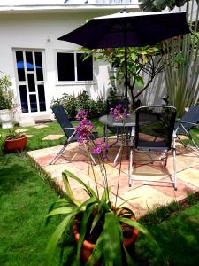 un patio con mesa, sillas y sombrilla en L'Epicurien en Cotonú