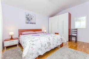 a white bedroom with a bed and a chair at Apartman Ivan in Kaštela