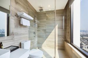 a bathroom with a toilet and a glass shower at The Quarter Ari by UHG in Bangkok