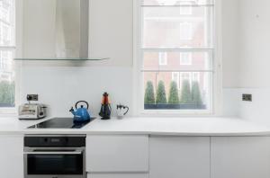 a kitchen with white cabinets and a window at Beautiful 1 Bedroom Apartment Ovington Square in London