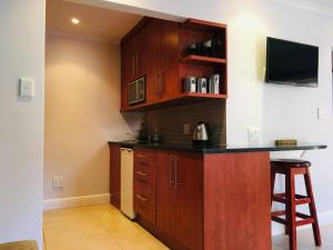 a kitchen with wooden cabinets and a tv on the wall at Cottage Kilkenny in Johannesburg +4 photos