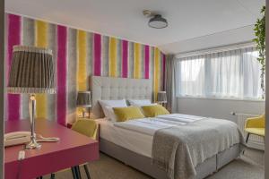 a bedroom with a bed and a desk and a colorful wall at Hotel Op Diek in Den Hoorn
