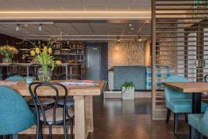 un restaurant avec des tables en bois et des chaises bleues dans l'établissement Hotel Op Diek, à Den Hoorn