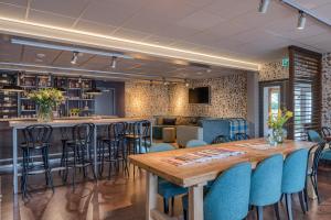 a restaurant with a wooden table and blue chairs at Hotel Op Diek in Den Hoorn