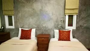 Cette chambre comprend 2 lits avec des oreillers rouges. dans l'établissement Pennapa Chalet, à Chalong