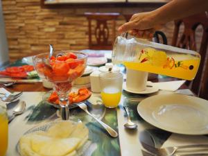 a person pouring orange juice into a bowl on a table at Xanadú B & B in Holguín