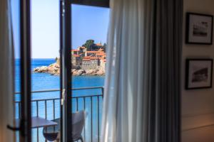 a room with a window with a view of the ocean at Hotel California by Aycon in Sveti Stefan
