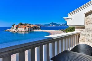 a balcony with a view of a house and the ocean at Hotel California by Aycon in Sveti Stefan