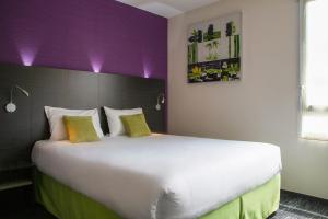 a large white bed in a room with a purple headboard at Kyriad Direct Limoges Nord in Limoges