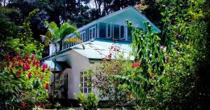 ein Haus mit blauem Dach und ein paar Blumen in der Unterkunft Surrey Bird Sanctuary & Holiday Resort in Welimada
