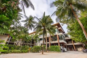 ein Gebäude mit Palmen davor in der Unterkunft J4 Samui Hotel - SHA Plus in Chaweng