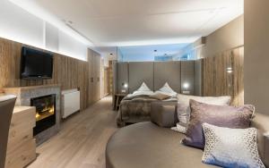 a hotel room with a bed and a couch and a television at Stroblhof Active Family Spa Resort in San Leonardo in Passiria