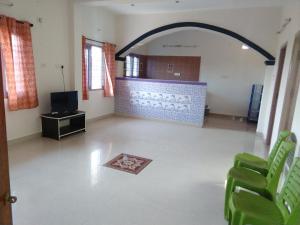 an empty living room with green chairs and a television at STHALAS in Mahabalipuram