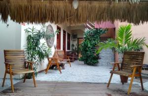 a patio with chairs and a umbrella and plants at Villa Guarani Jeri in Jericoacoara