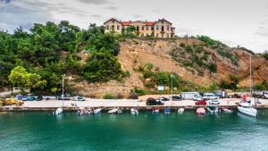 a group of boats in a marina with a house on a hill at Delikos House in Limenaria