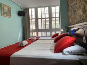 a bedroom with two large beds with red pillows at Hostal Hotil Coruña Centro in A Coruña
