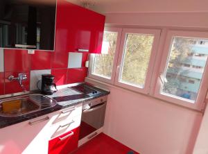 a red kitchen with a stove and two windows at Studio apt. Downtown in Split