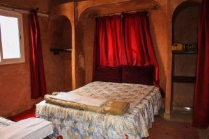 a bedroom with a bed with red curtains at Maison berbère in Ouarzazate