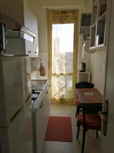 アスティにあるOasi di tranquillitàのキッチン(冷蔵庫、テーブル付)、窓が備わります。