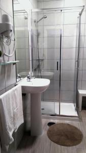 a bathroom with a sink and a glass shower at Alojamento Ar e Sol in Guimarães