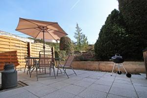 eine Terrasse mit einem Tisch, einem Sonnenschirm und einem Grill in der Unterkunft Gite-les-myrtilles in Corcieux