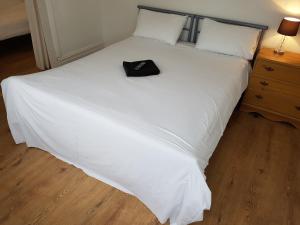a large white bed with a black hat on it at Boscombe Reef Hotel in Bournemouth