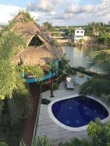 a resort with a thatch roof and a swimming pool at Hotel Palmera Beach Cartagena in Cartagena de Indias