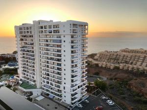 ein hohes weißes Gebäude vor dem Meer in der Unterkunft The Pradise of Ana Vemar Exclusive Apartament in Playa Paraiso