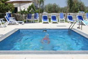 una persona nadando en una piscina con sillas azules en Case Vacanza SANT'AGOSTINO Siracusa, en Siracusa