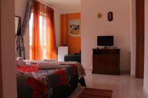 a bedroom with a bed and a tv and a window at B&B Su Nuraghe in SantʼAntìoco