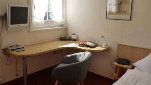 um quarto com uma secretária com uma cadeira e uma televisão em Gasthof zur Post em Schmallenberg