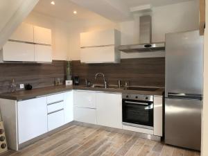 uma cozinha com armários brancos e um frigorífico de aço inoxidável em Villa Cocooning proche Cannes em Vallauris