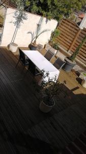 une table et des chaises blanches sur une terrasse avec des plantes dans l'établissement les Pénates appartement terrasse, à Saint-Max
