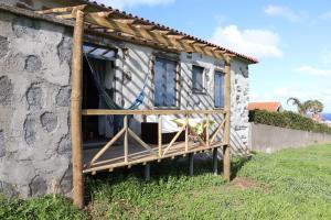 a tiny house with a porch on a stone wall at Casas da Quinta in Santa Cruz das Flores