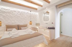 a white bedroom with a large bed and a bathroom at Villa Adriana Hotel in Agios Prokopios