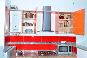 a kitchen with red cabinets and a microwave at Appart Clim Wifi 700m de la Plage in Saïdia